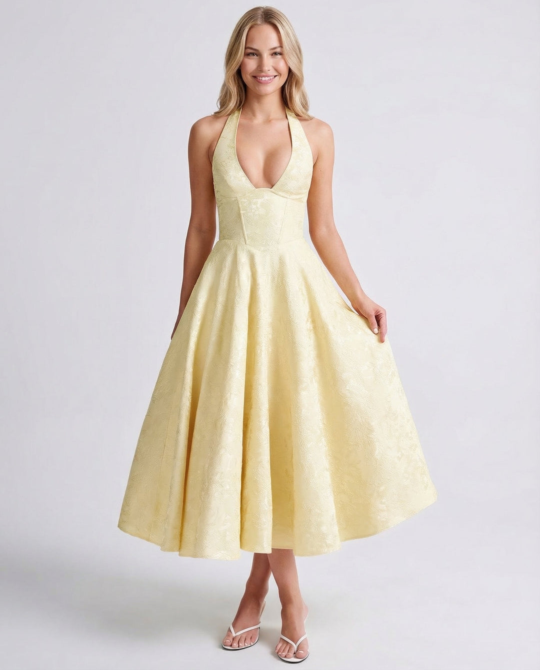 Female wearing a sleeveless halter midi dress with a flared skirt against a plain background.