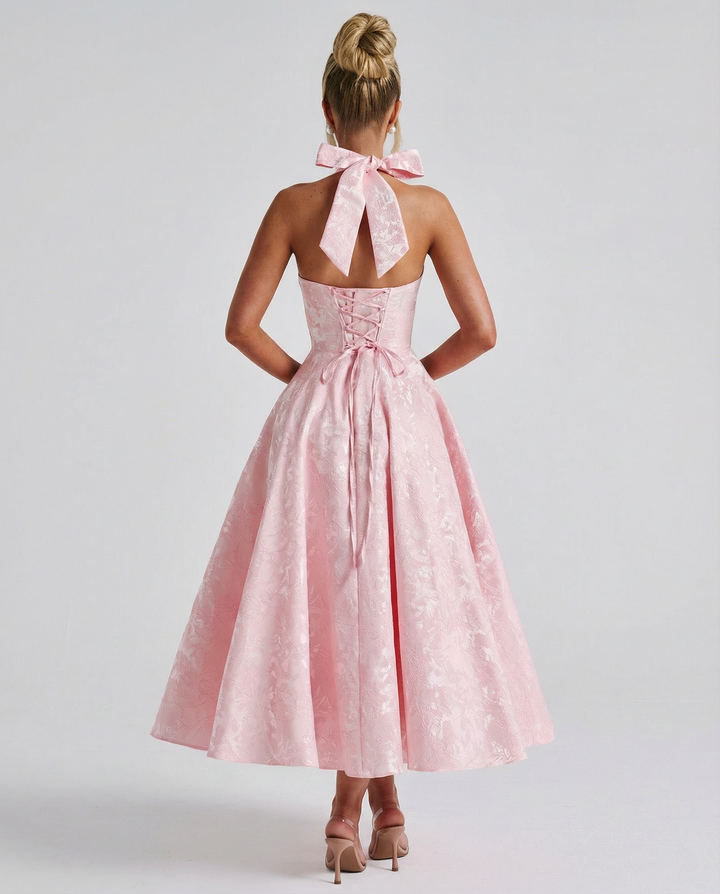 Woman posing in a sleeveless halter dress with a flowing midi-length silhouette.