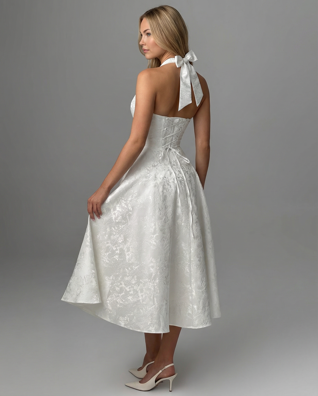 Female model displaying a sleeveless dress with a structured upper design on a plain background.