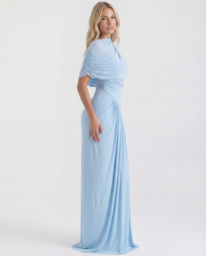 Female model wearing an elegant long dress with pleated bodice on a plain background.