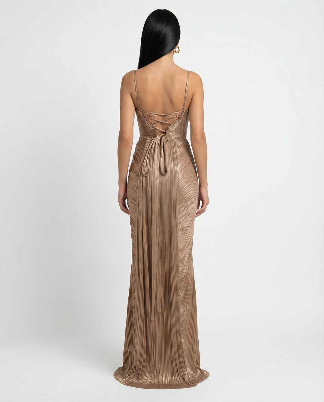 Woman in a glossy pleated maxi dress with slim straps against a plain background.
