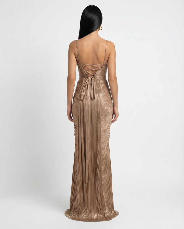 Woman in a glossy pleated maxi dress with slim straps against a plain background.