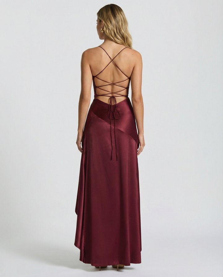 Woman in a smooth satin-look dress with lace-up back on a plain background.