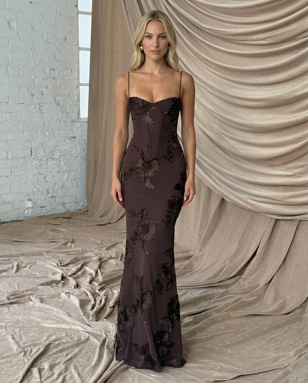 Female in a fitted corset-style dress with slim straps and full-length hemline.
