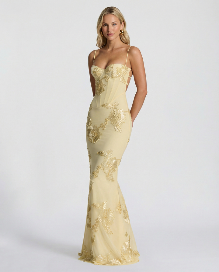 Female wearing a sweetheart neckline maxi dress with floral appliqué accents on a plain backdrop.