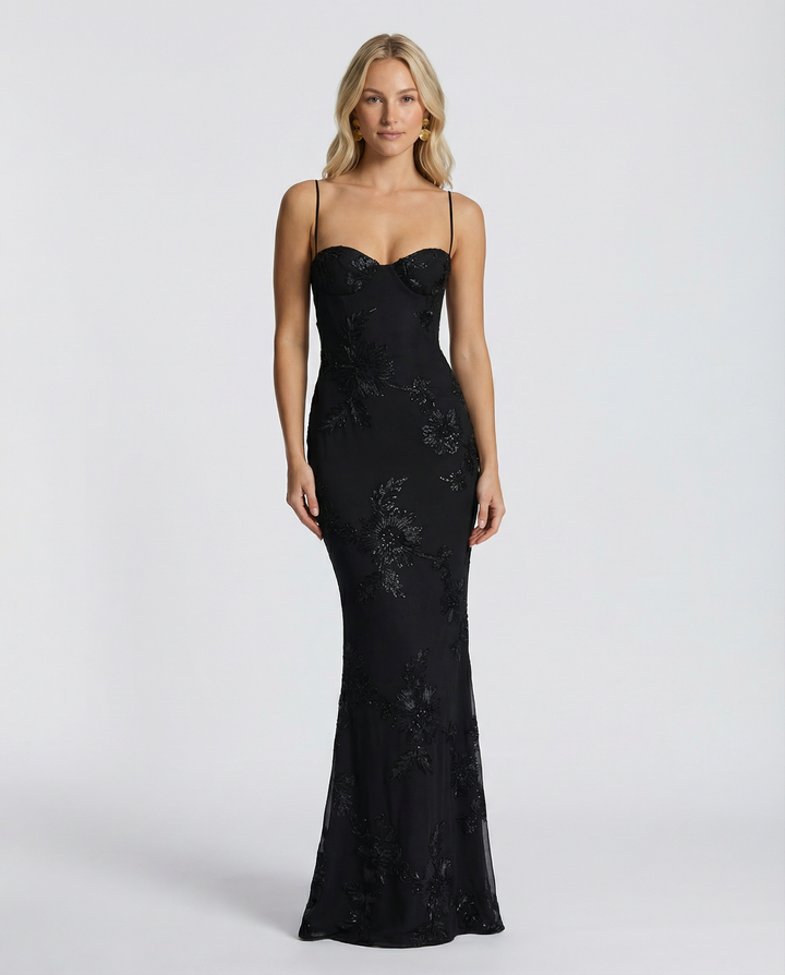 Model wearing a fitted formal maxi dress with floral appliqué and slim shoulder straps.