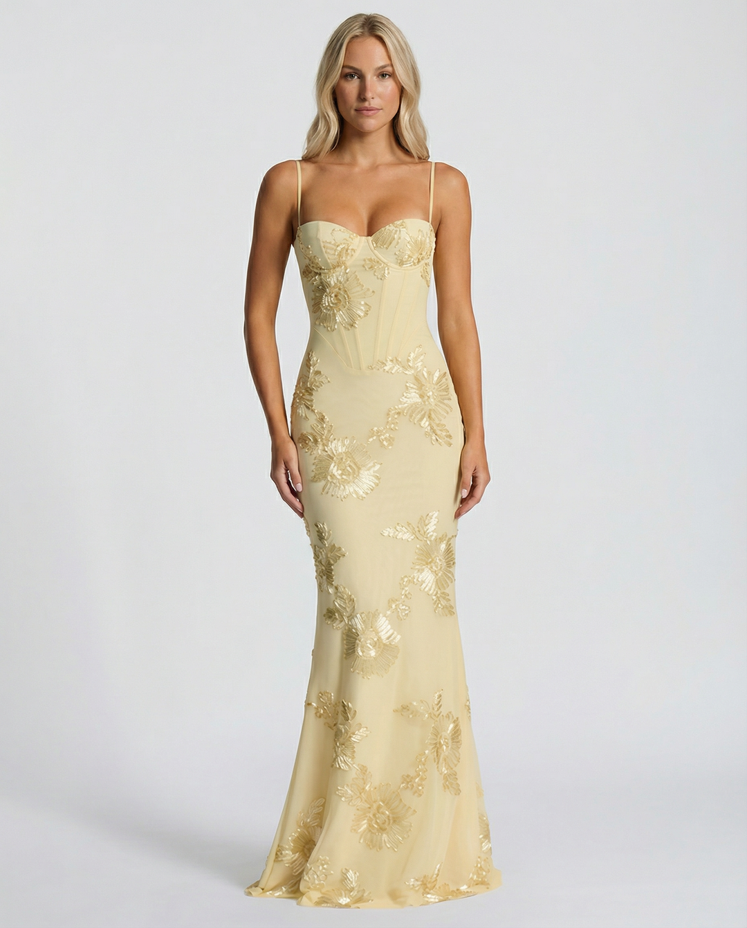 Woman in a sleeveless corset-style maxi dress with lace-up back on a plain background.