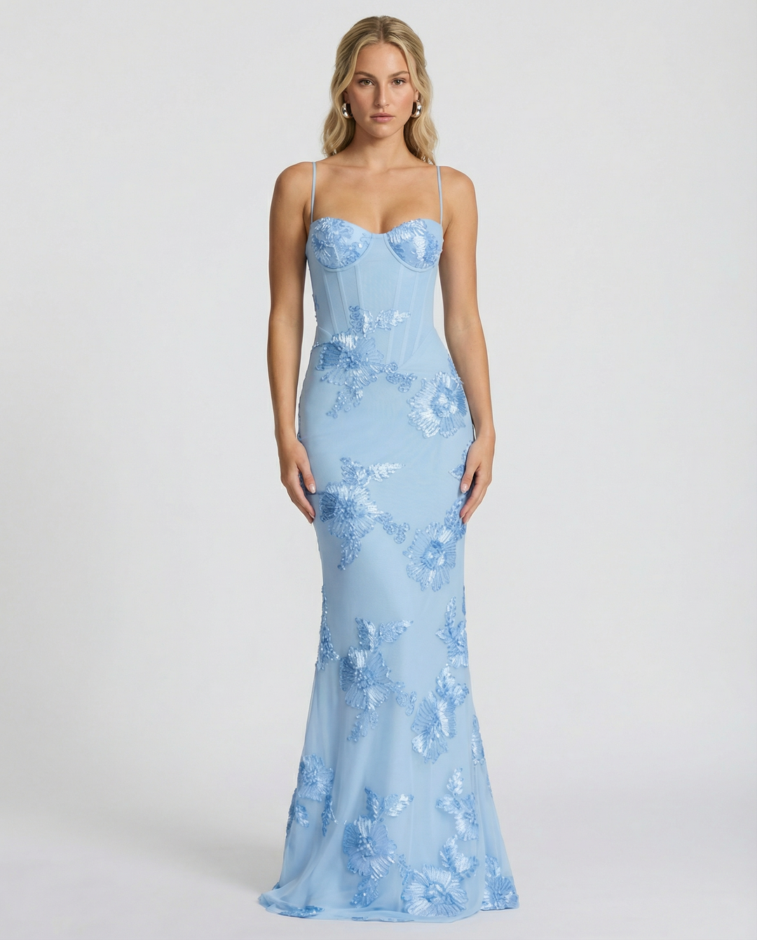 Woman styled in a fitted evening maxi dress with lace-up back detail against a plain background.