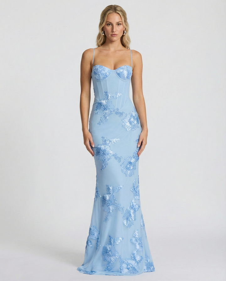 Woman styled in a fitted evening maxi dress with lace-up back detail against a plain background.