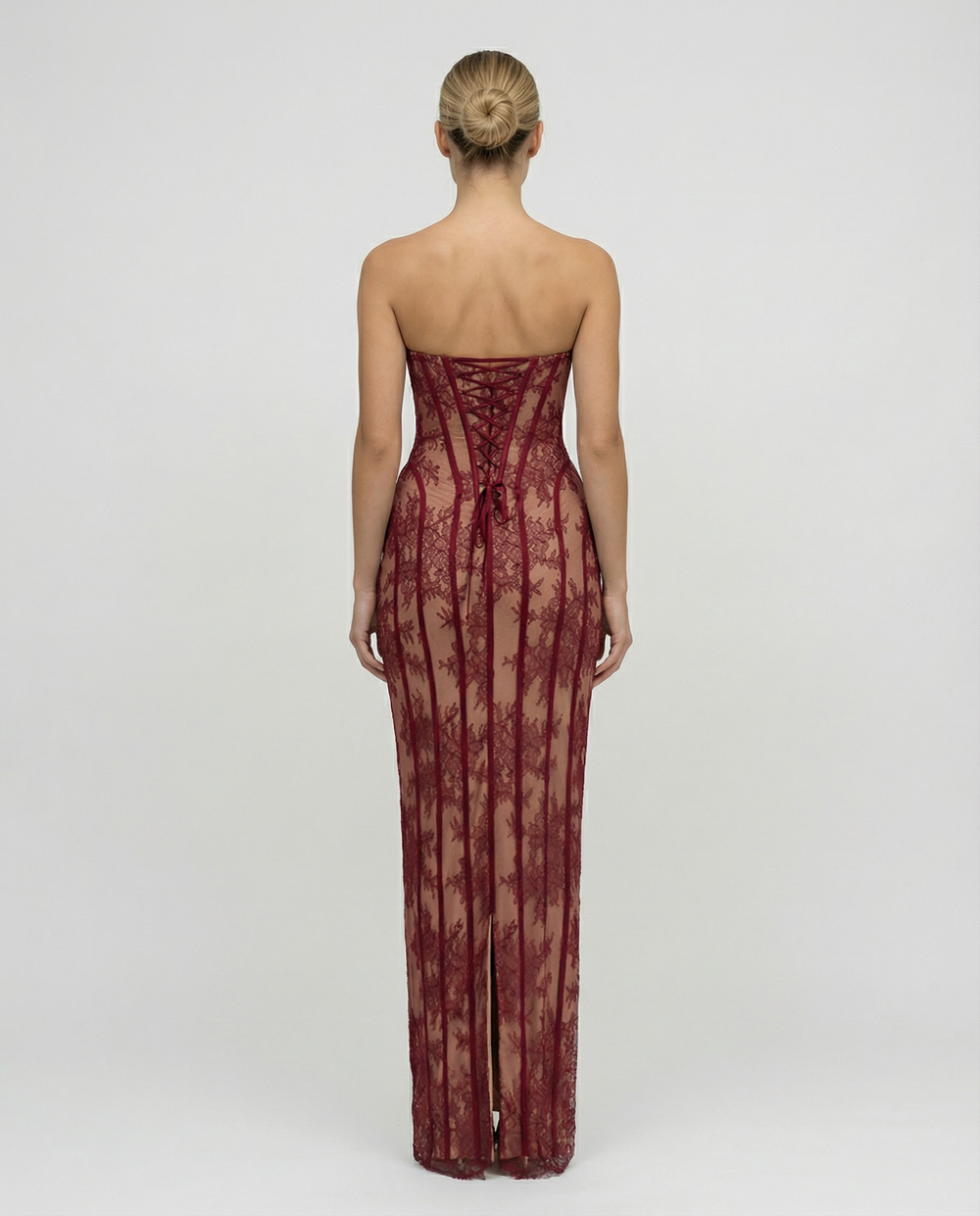 Female in a fitted full-length lace overlay dress with sweetheart neckline on a plain background.