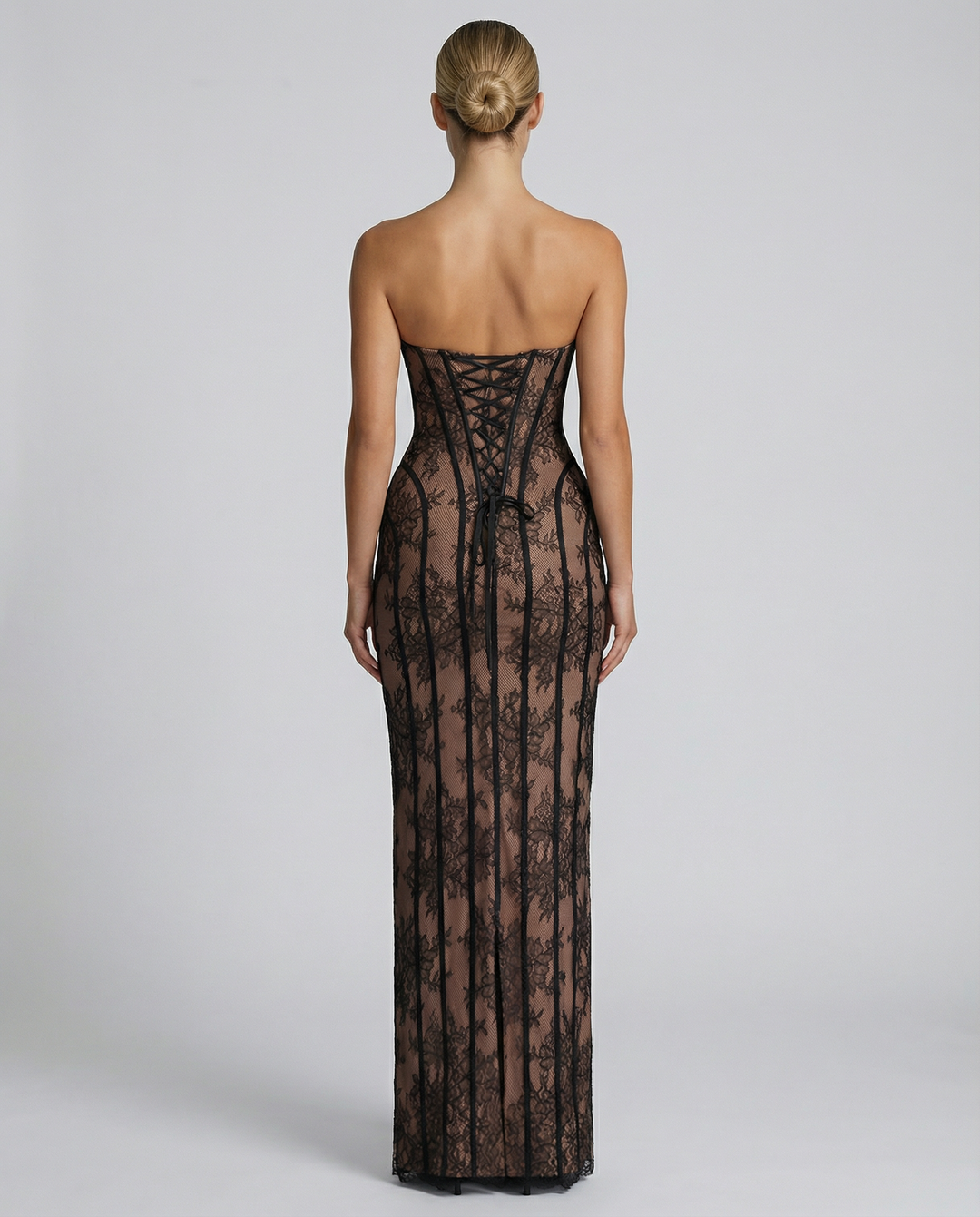 Woman wearing a sleeveless sweetheart neckline evening dress on a plain background.