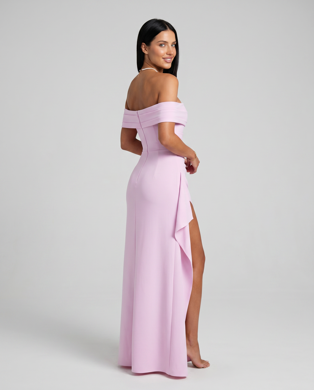 Female model posing in a high waist evening dress against a plain background.