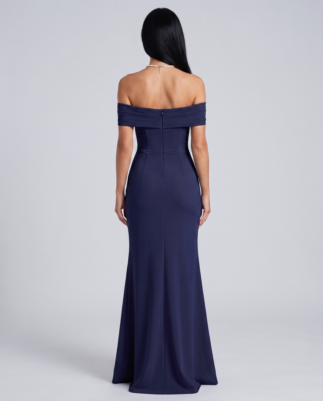 Woman wearing an elegant off shoulder maxi dress on a plain background.
