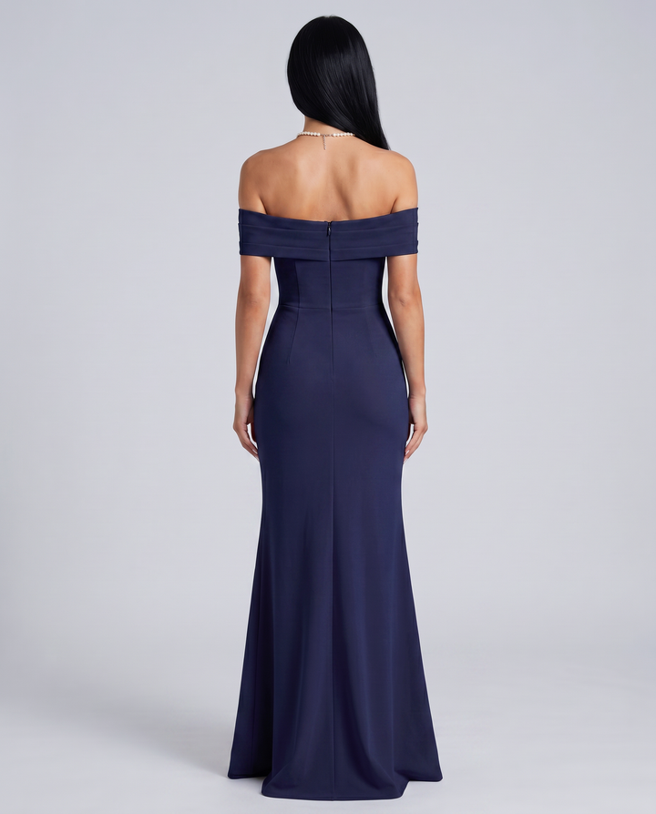 Woman wearing an elegant off shoulder maxi dress on a plain background.