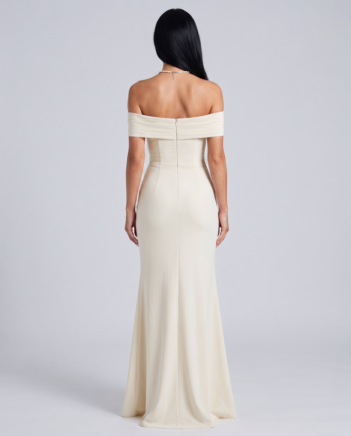 Woman wearing a fitted formal dress with side slit on a plain background.