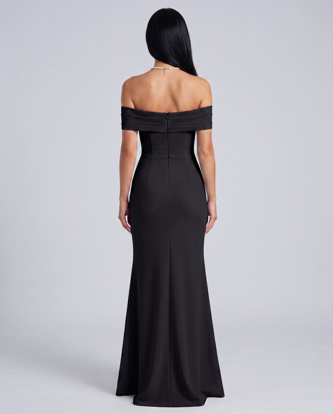Woman styled in a sleek sleeveless evening dress on a plain background.
