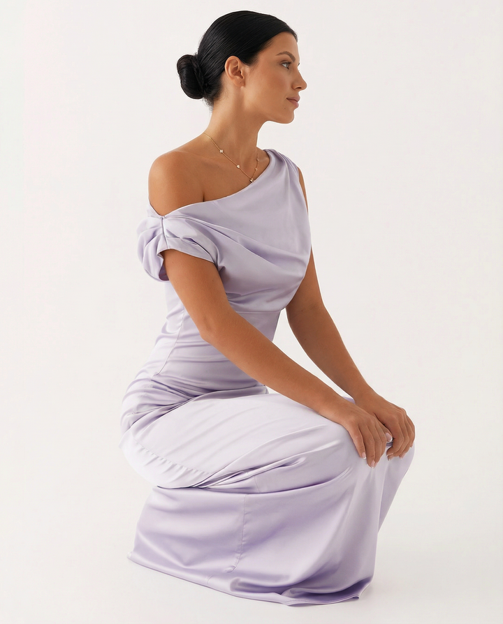 Female model wearing a sleeveless asymmetrical dress on a plain background.