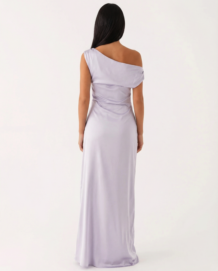 Woman in a one-shoulder formal maxi dress on a plain background.