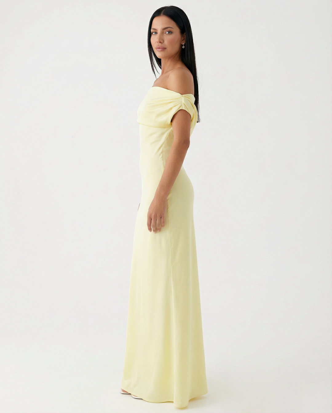 Woman styling a draped satin maxi dress on a plain background.
