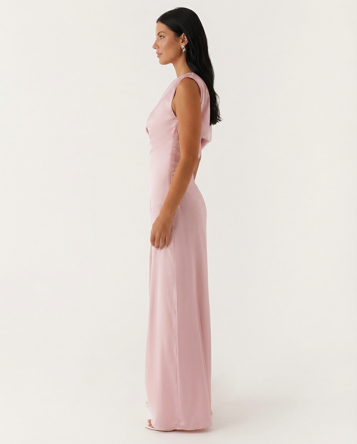 Female model showcasing an asymmetrical neckline maxi dress on a plain background.