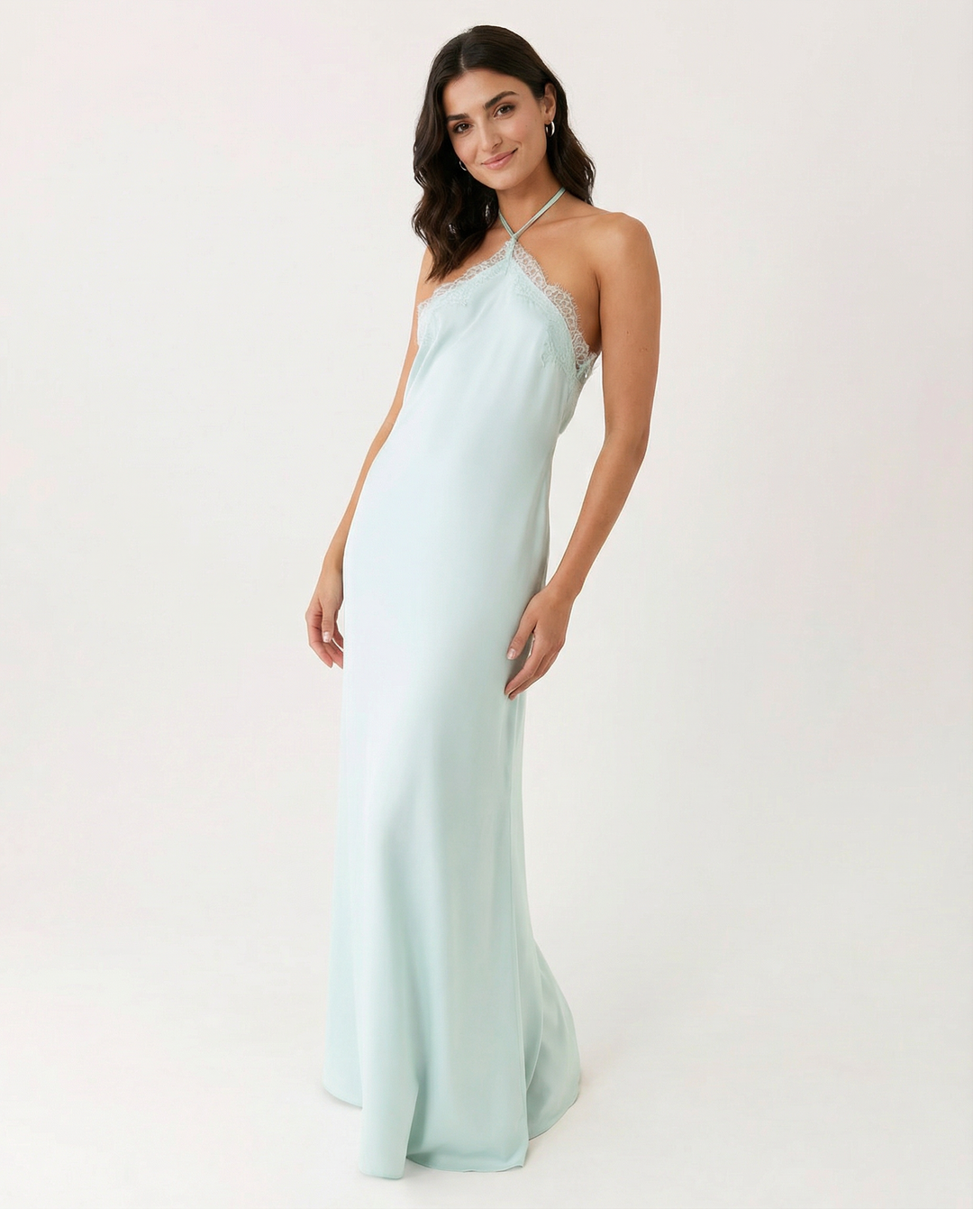 Female model in a full-length blue dress with lace trim neckline on a plain background.