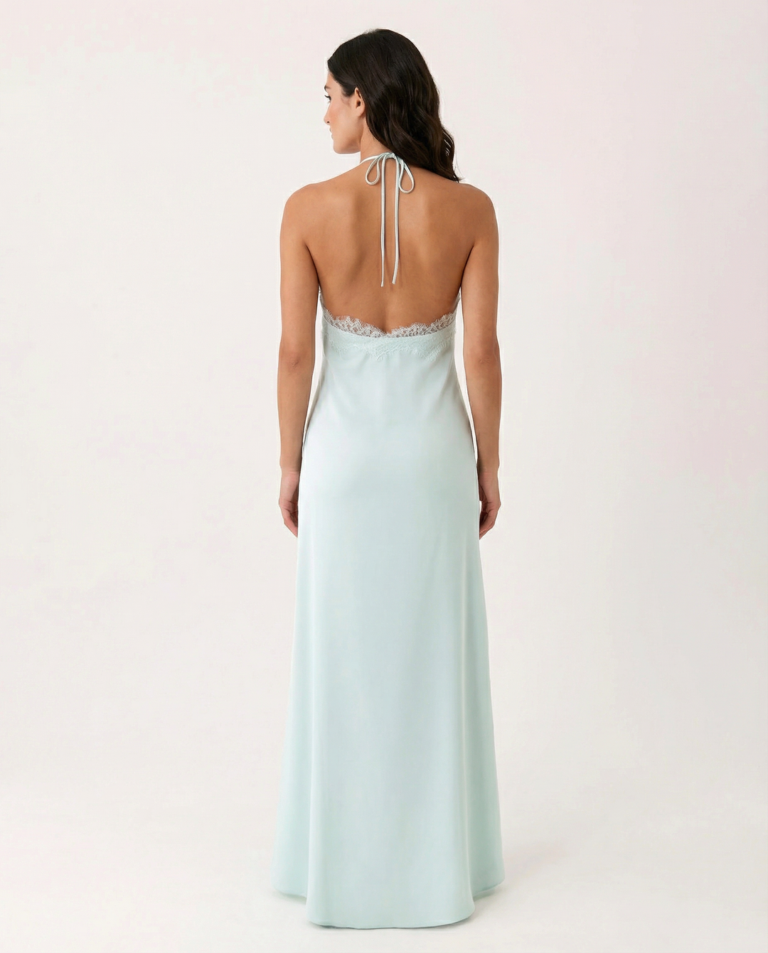 Woman in a flowing blue sleeveless maxi dress with halter neckline on a plain background.