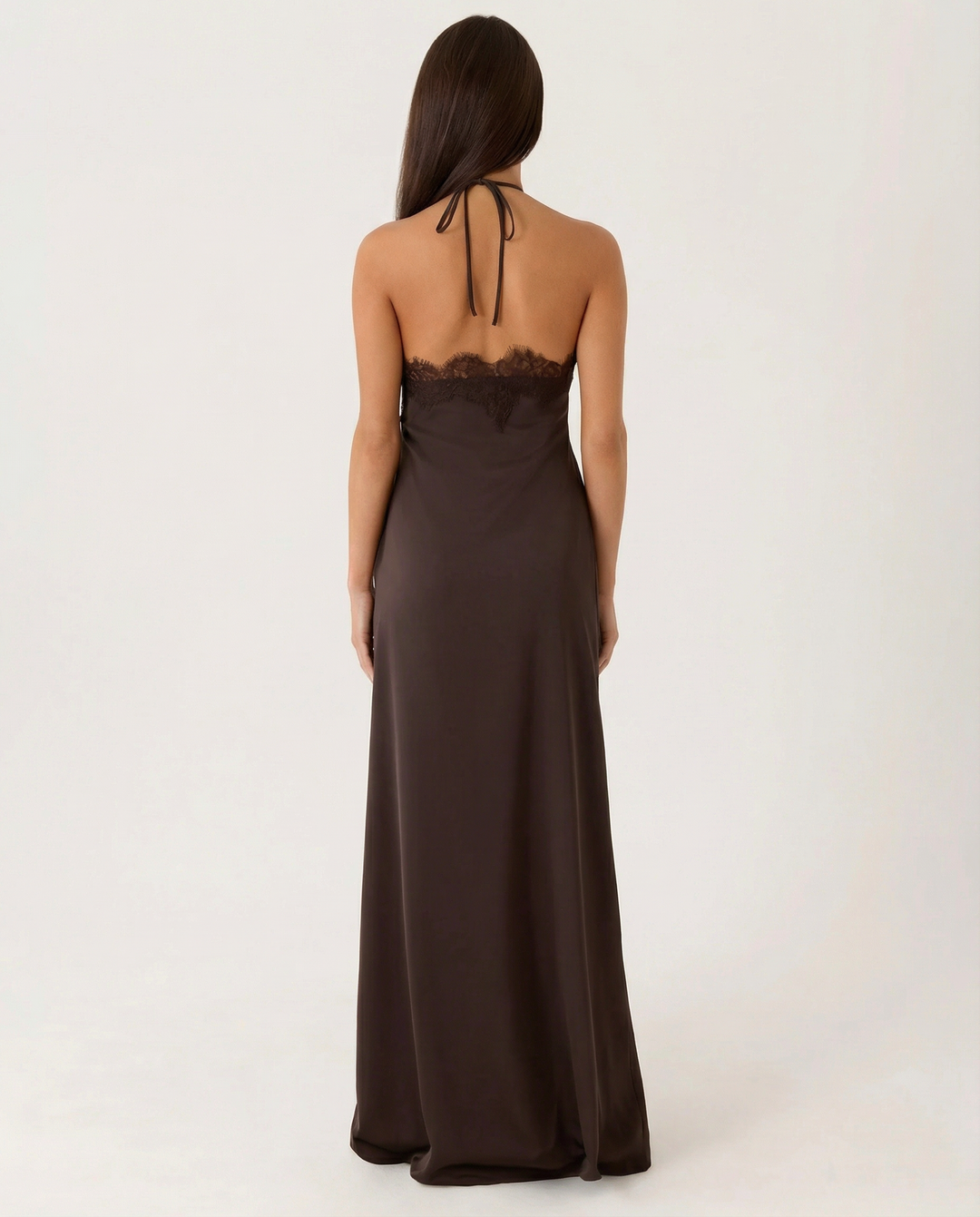 Model in a  halter neck dress with flowing skirt on a plain background.
Female 