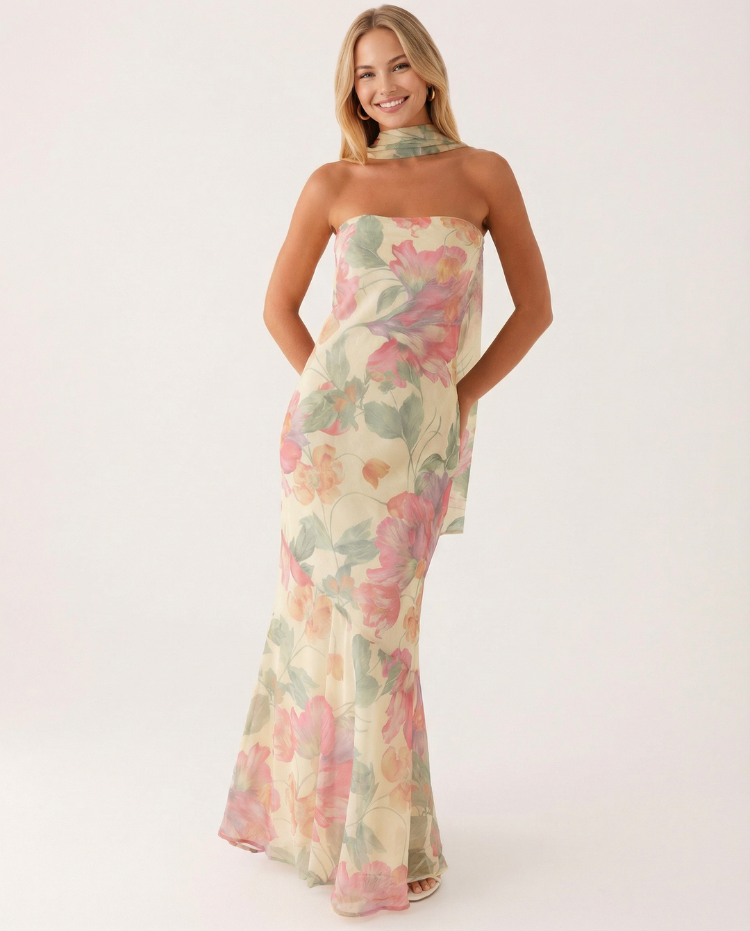 Woman styled in a long floral dress with a matching neck scarf.