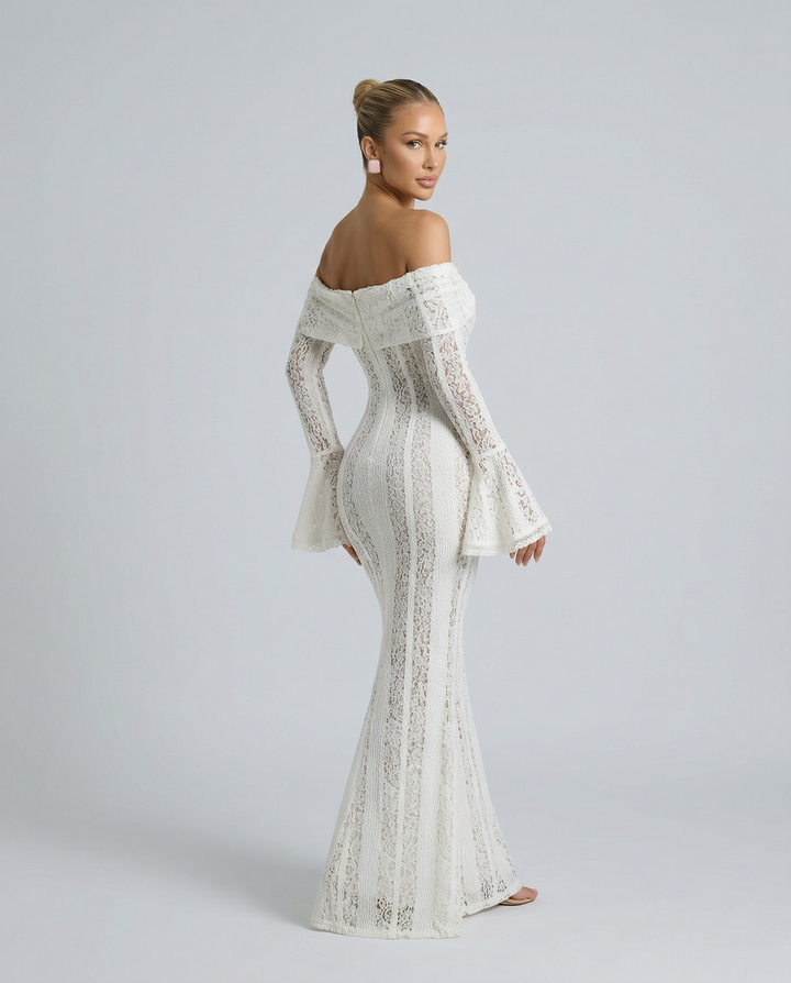 Female model in a white off shoulder evening dress with flared hem on a plain background.
