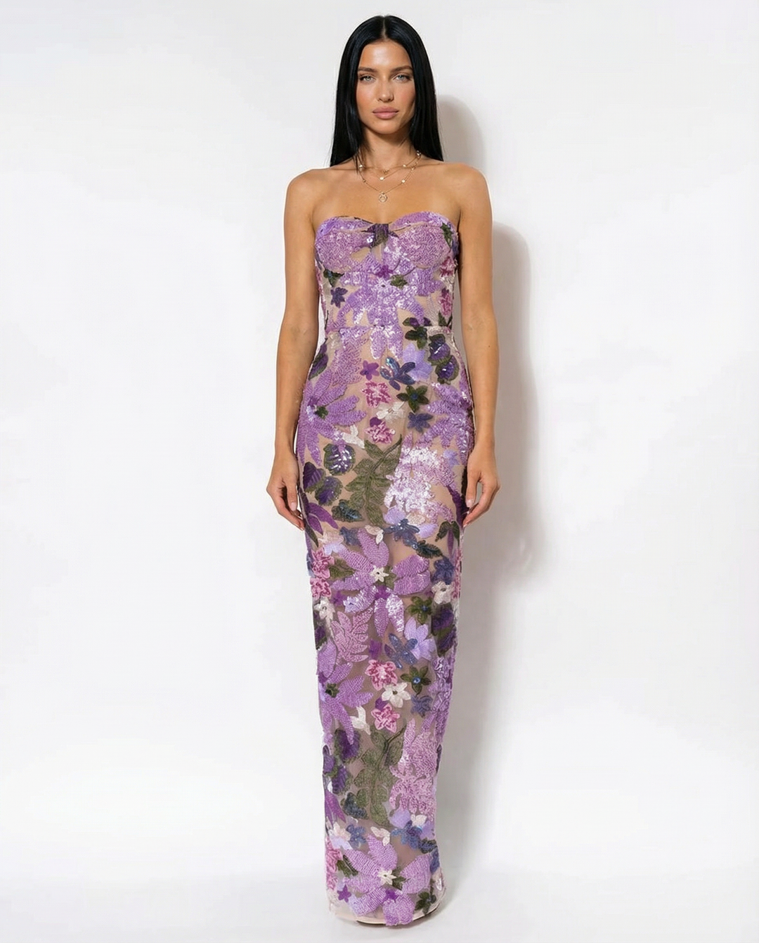 Woman posing in a purple strapless floral sequin dress with fitted waist on a plain background.