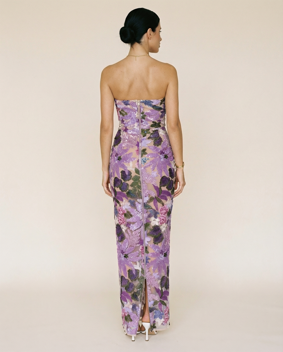 Woman wearing a purple strapless maxi dress with floral sequin embroidery on a plain background.