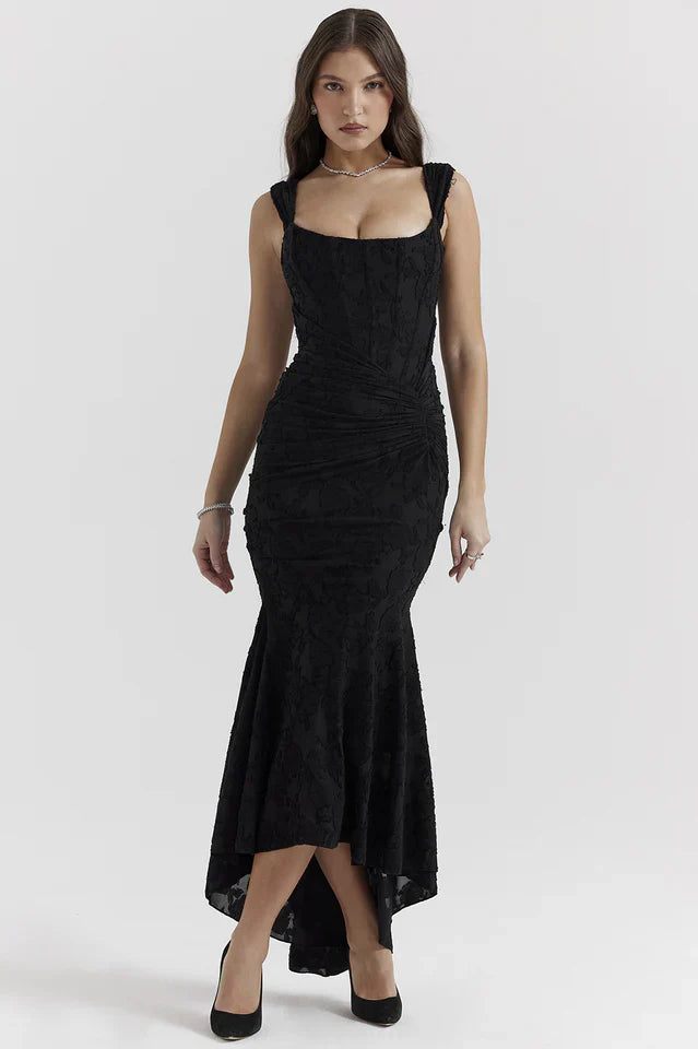 Female model wearing a black maxi dress with wide straps against a plain background.