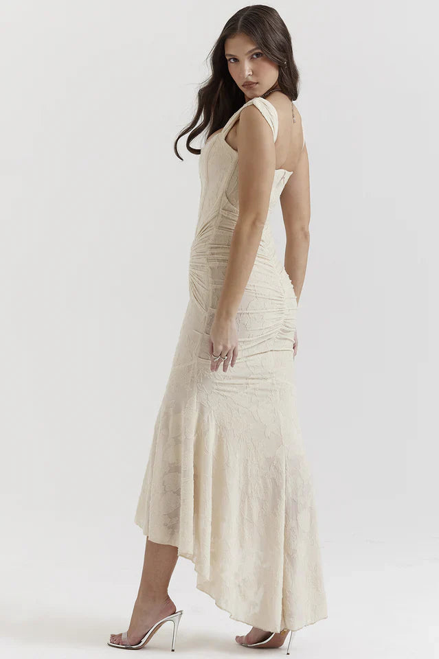 Woman in a cream square neck dress with fitted waist on a plain background.