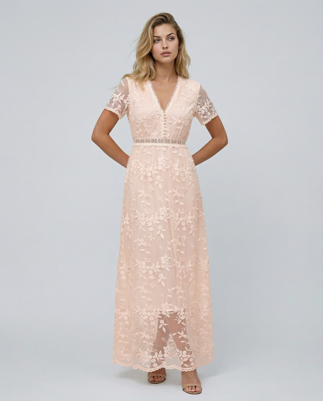 Woman posing in a layered floral formal dress with a plain studio background.