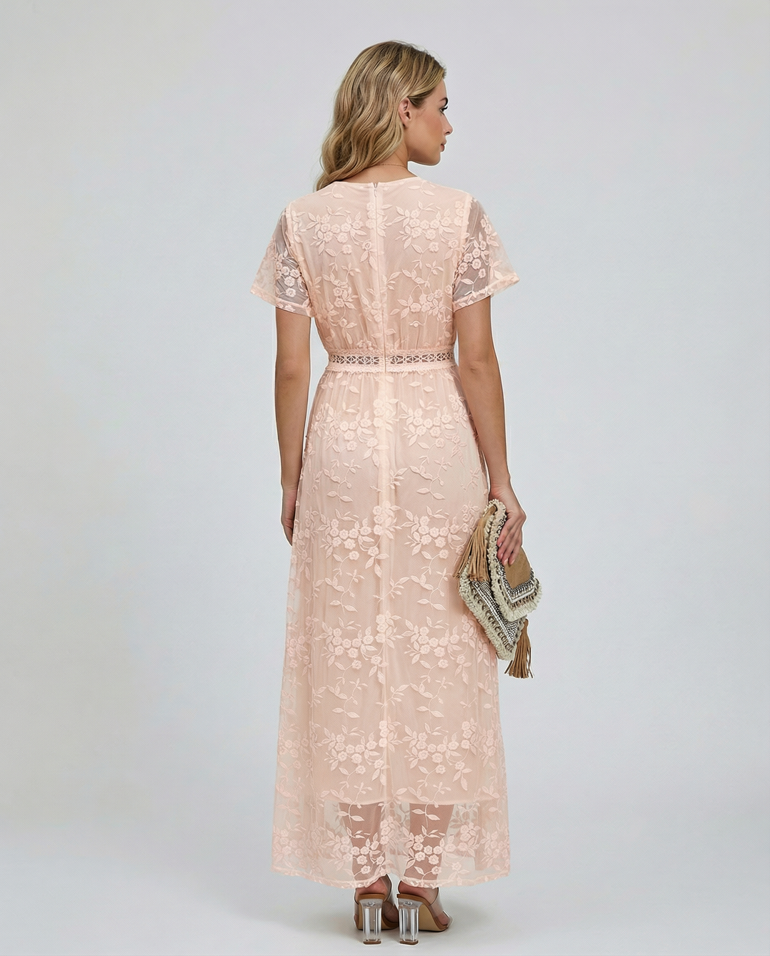 Female model showcasing a floral maxi dress with long sheer sleeves against a plain background.