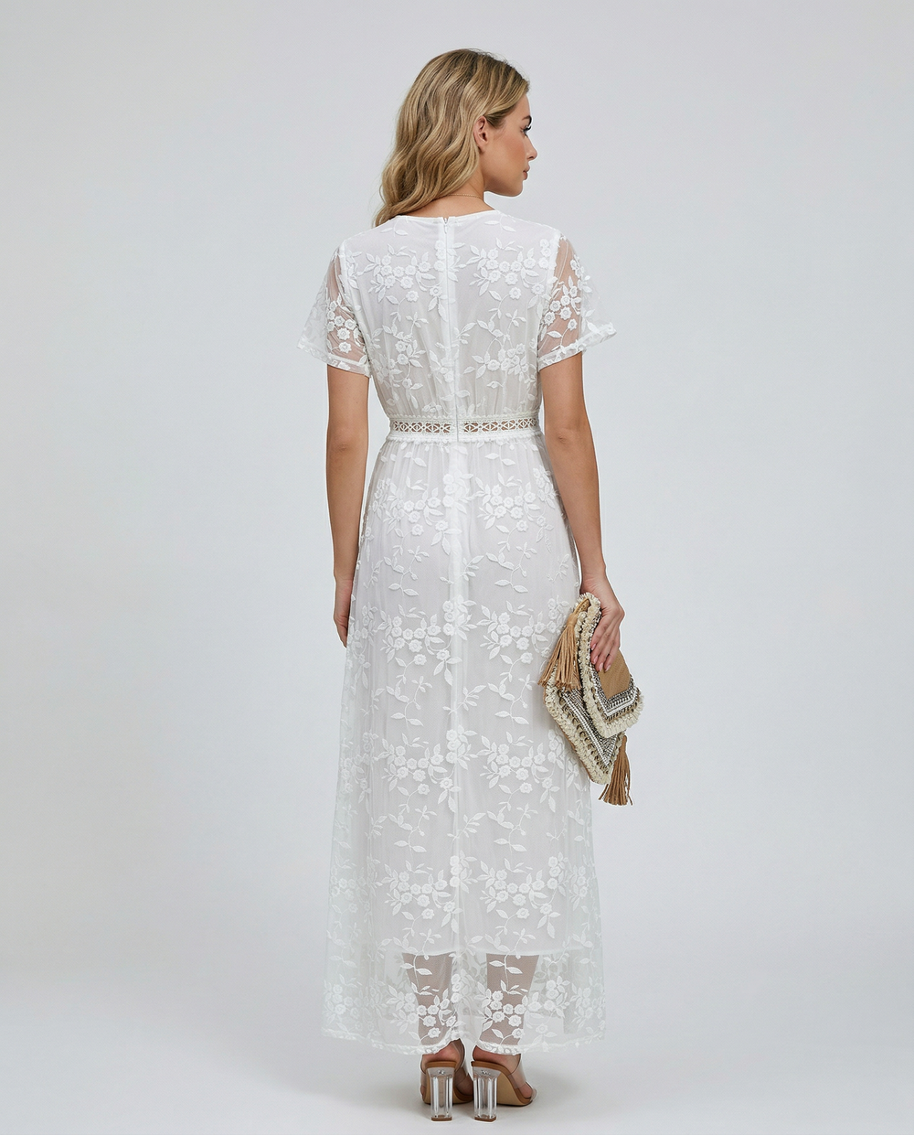 Woman modeling a long floral dress with layered ruffle detail on a plain background.