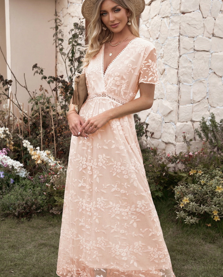 Woman modeling a formal floral dress with soft layered movement on a plain background.