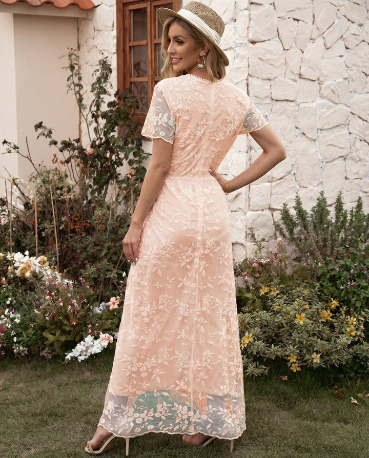 Female model wearing a high neck floral maxi dress with ruffle accents on a plain background.