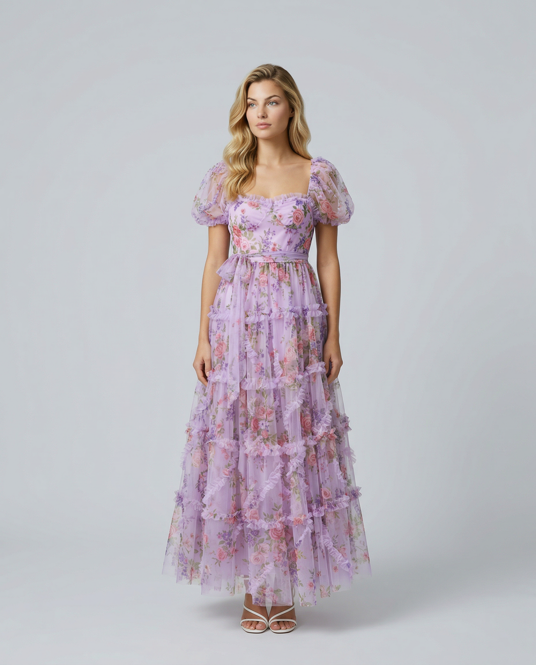 Model in a soft floral tiered dress with short puff sleeves against a plain backdrop.