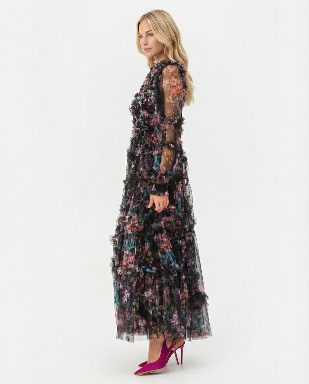 Model wearing a long floral ruffle dress with sheer sleeves on a plain background.