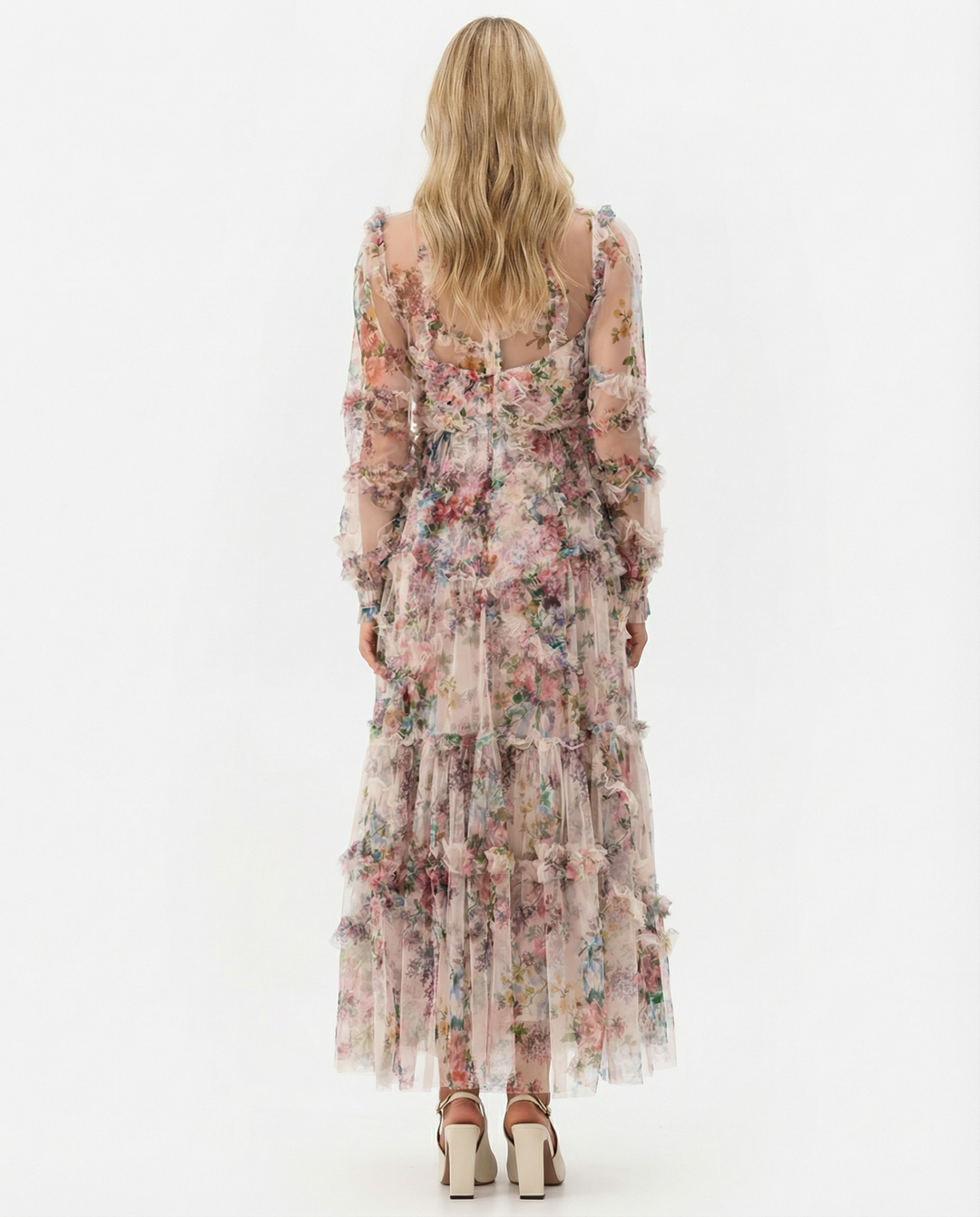 Model in a flowing tiered floral maxi dress on a plain background.