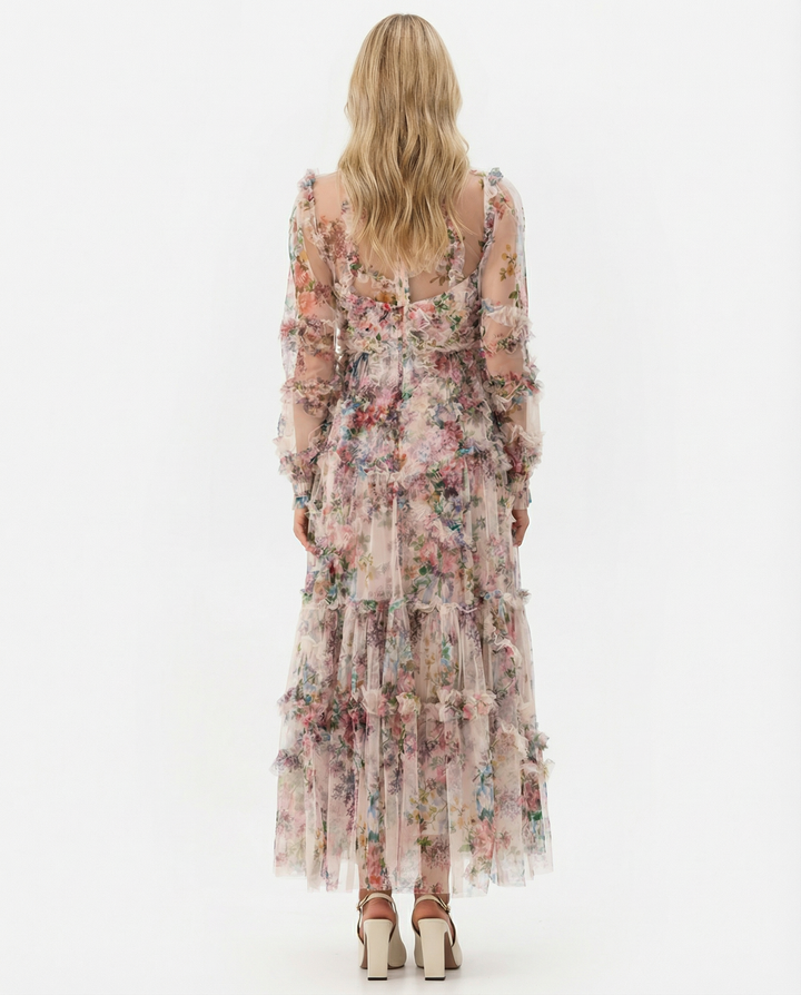 Model in a flowing tiered floral maxi dress on a plain background.