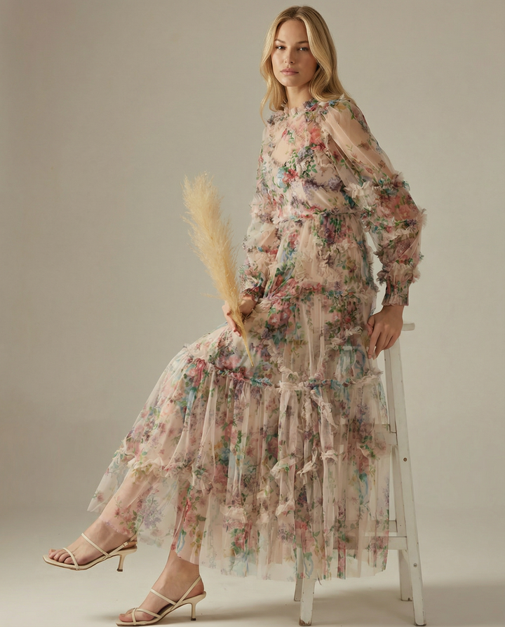 Model in a floral long sleeve maxi dress with layered skirt on a plain background.
