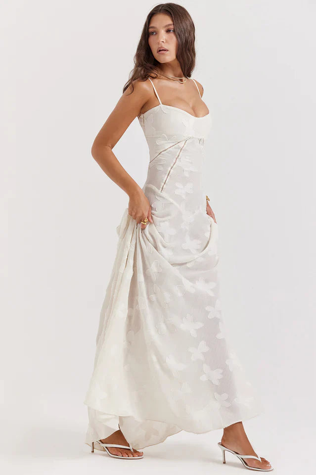 Female model showing a sleeveless floral maxi dress with a lace-up back on a plain background.