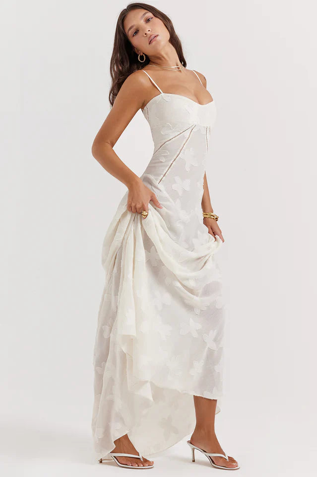 Woman wearing a long floral dress with a fitted bodice on a plain background.