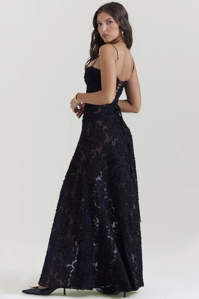 Woman in a floral maxi dress styled for warm-weather occasions on a plain background.