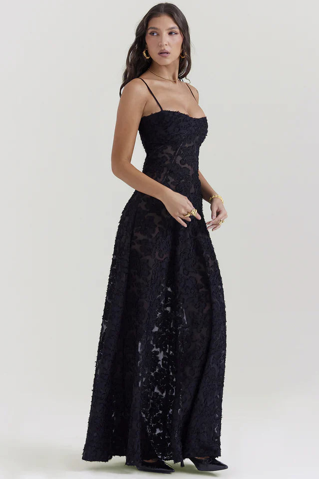 Model wearing a long floral dress with a defined bodice on a plain background.