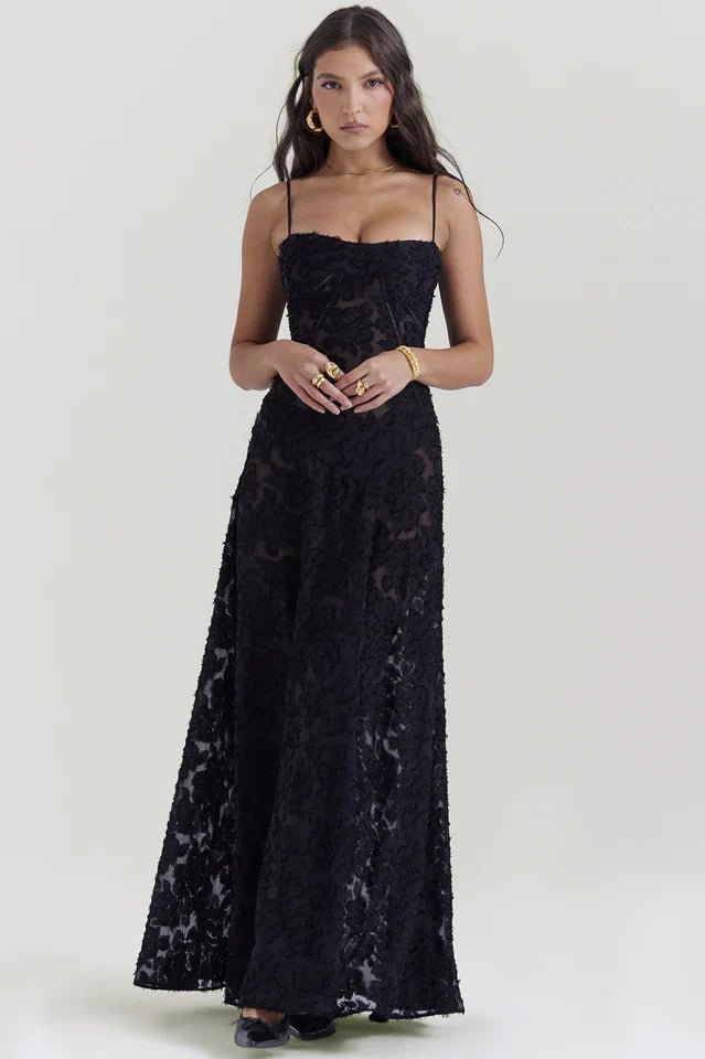 Female model wearing a floral sleeveless dress with soft skirt drape on a plain background.