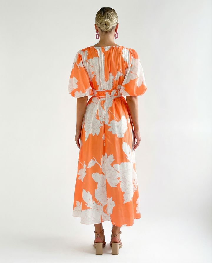 Model in a floral V-neck midi dress with short puff sleeves on a plain background.