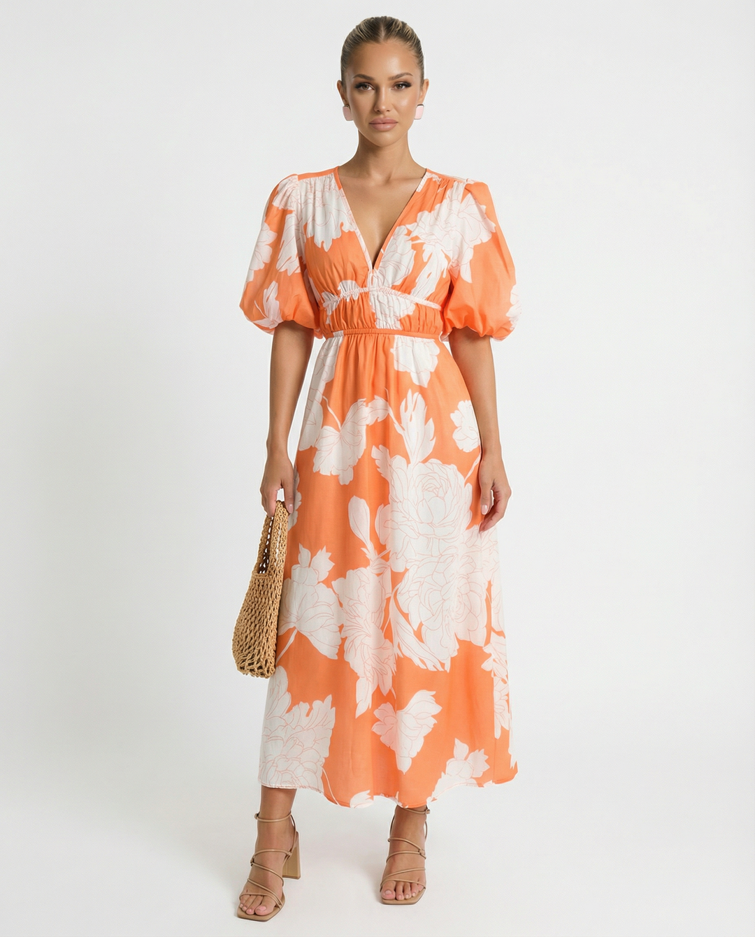 Woman wearing an orange floral midi dress with a relaxed silhouette on a plain background